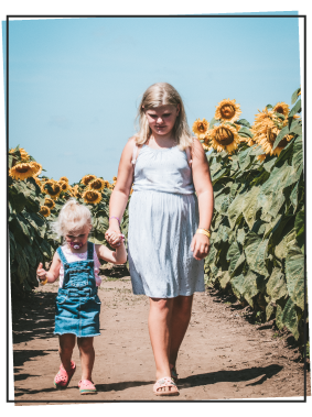 Girls walking through a sunflower field 